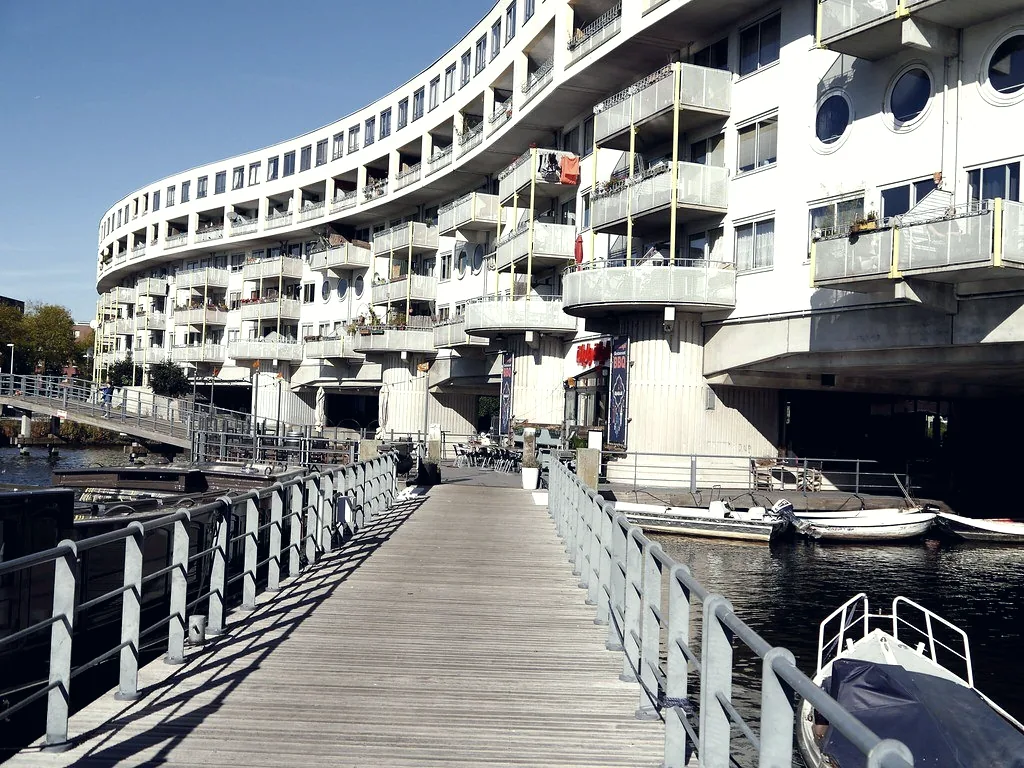 A curved residential apartment building seen from a waterside walkway